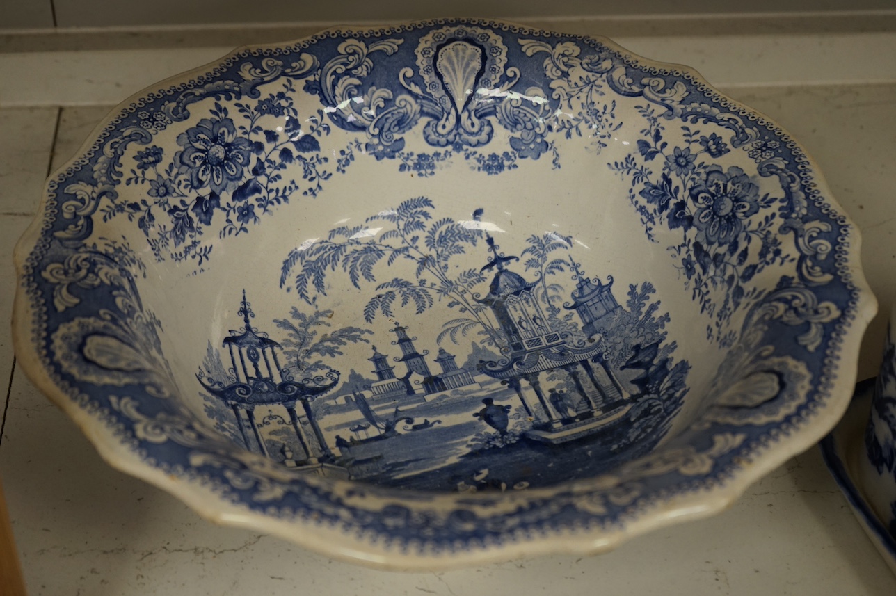 A group of blue and white ceramics to include Ironstone cheese dome and jug, a basin and twin handled cups, largest 36cm in diameter. Condition - varies